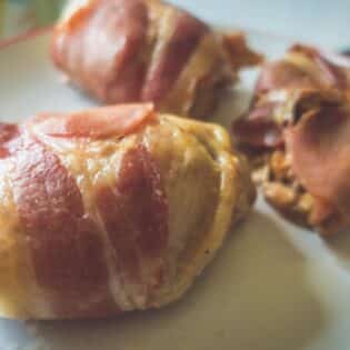 Bacon-wrapped chicken thighs on a baking tray